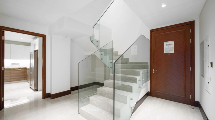 Modern staircase with glass railing near wooden door